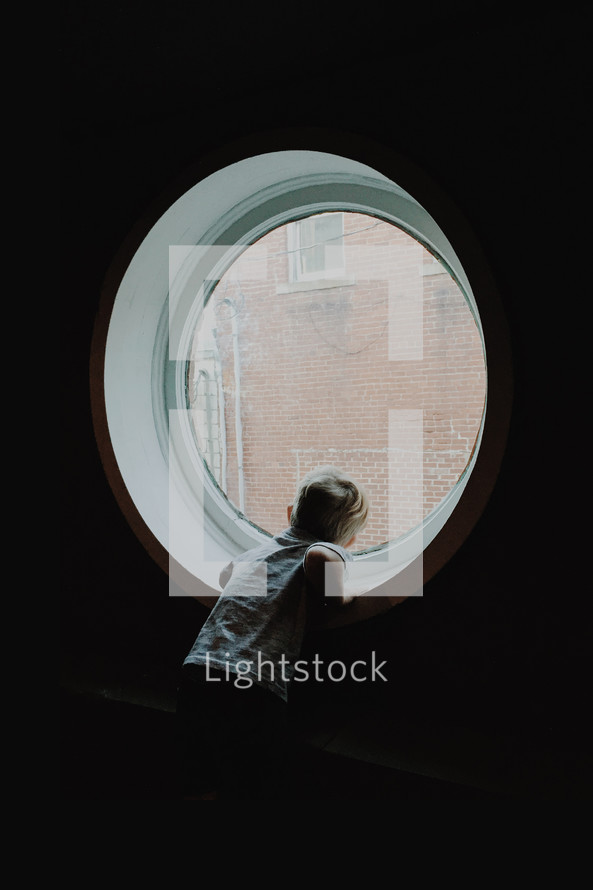 little boy looking out of a porthole window