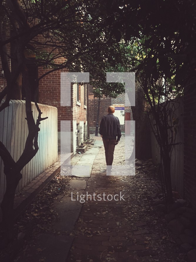 a man walking through an alley 