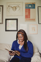 African-American woman reading a Bible on a couch 