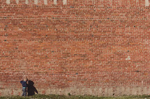 toddler boy in front of a brick wall 