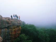 Family standing on a cliff above the tree tops.