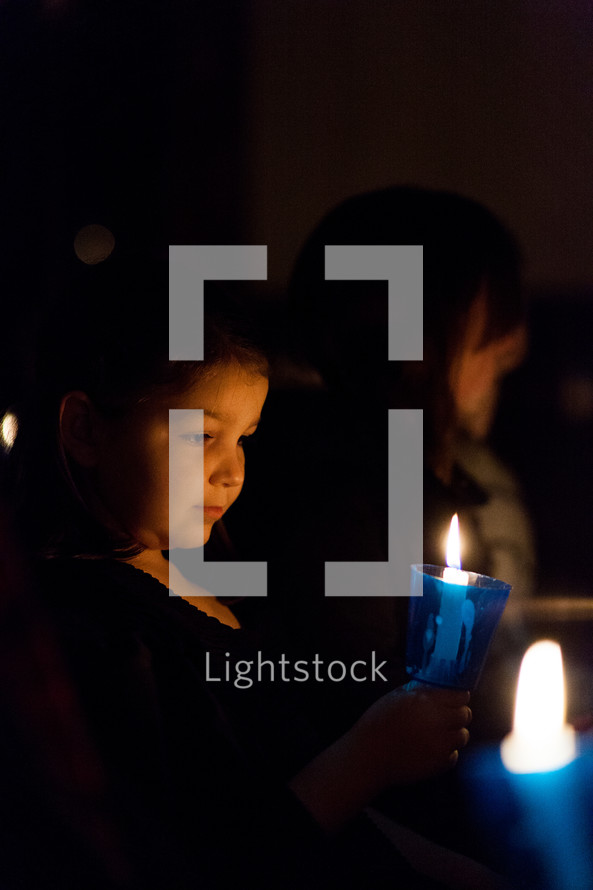 a child holding a candle at a Christmas Eve Candlelight service 