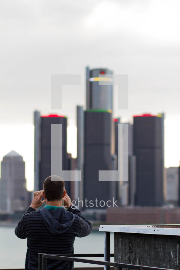 man taking a picture of city buildings on a cruise ship 