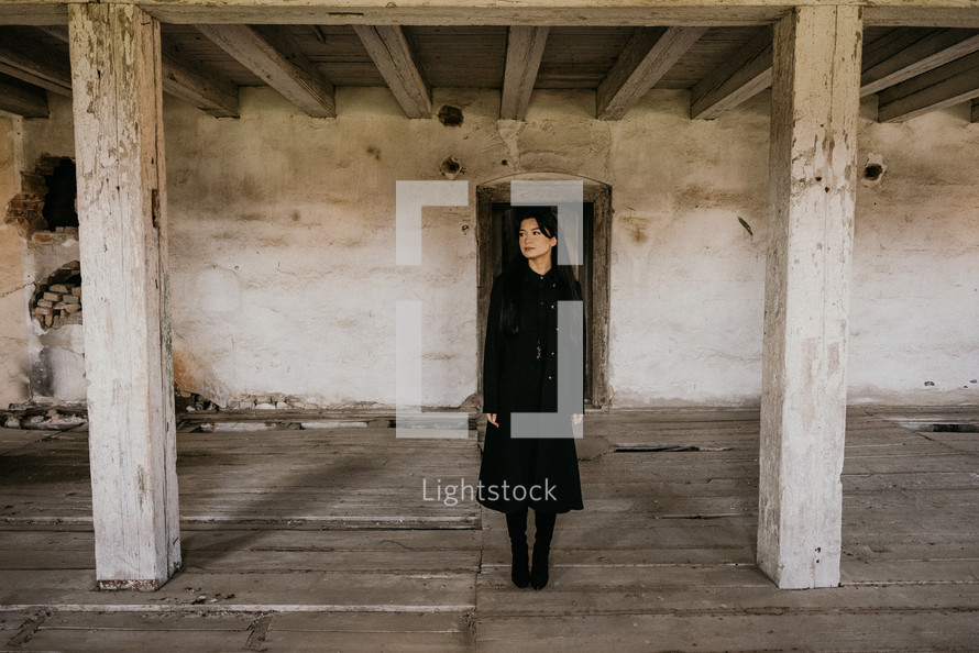 Woman in black standing in old, empty building