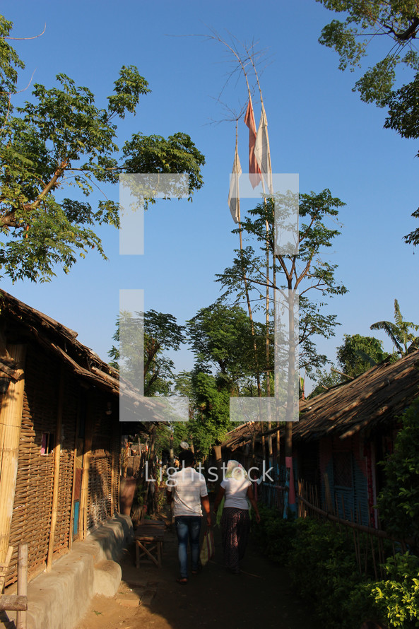 flags on trees above and alley between huts 