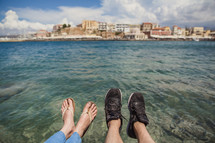 feet hanging over ocean water 