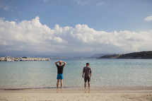 men standing in water on a beach in Greece 