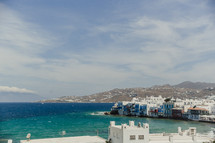 A city of white buildings lining along the shore of a blue sea.