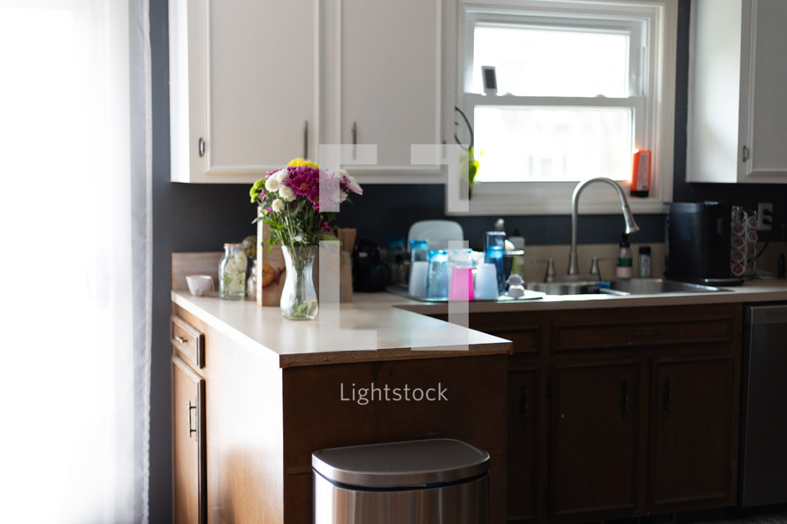 Kitchen interior with counter space and flower vase decoration with dishes in drying rack next to sink