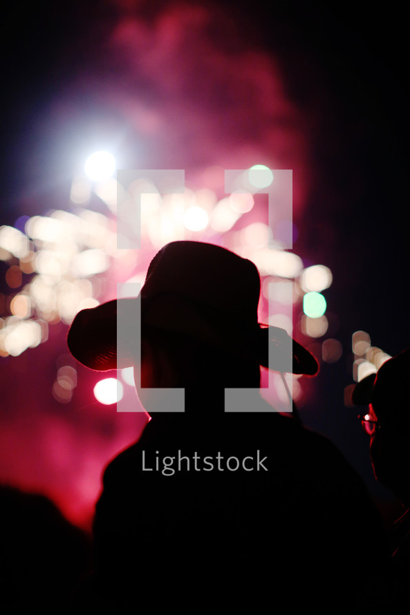 silhouette of a child in a cowboy hat watching fireworks 