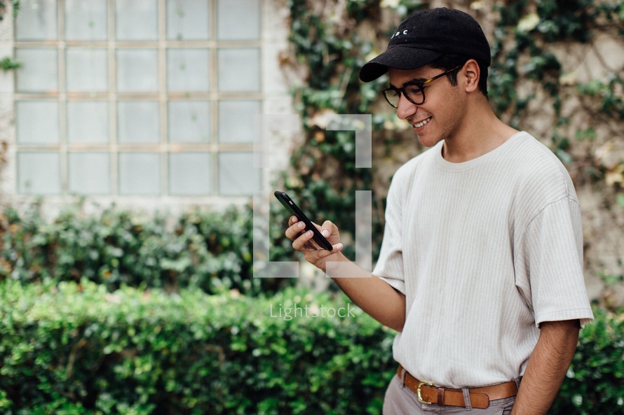 a man looking at a cellphone screen smiling 