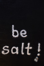 The words, "be salt," written with salt on a table.