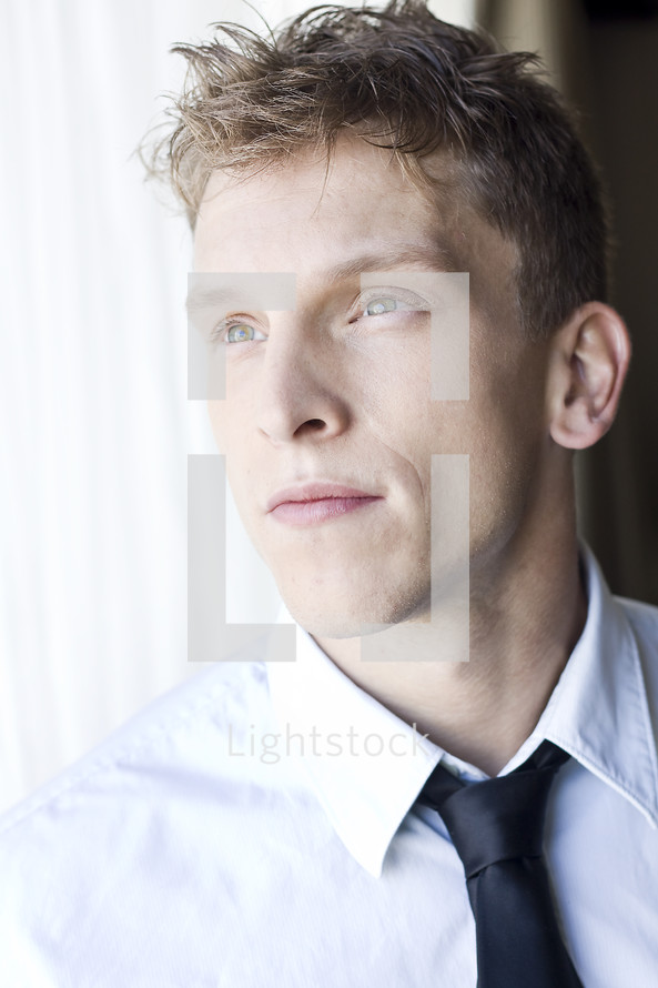 Man in shirt and tie looking out the window.
