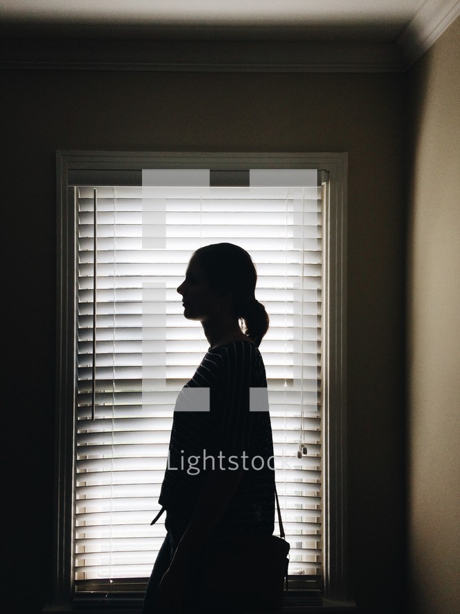 silhouette of a woman standing in a window 