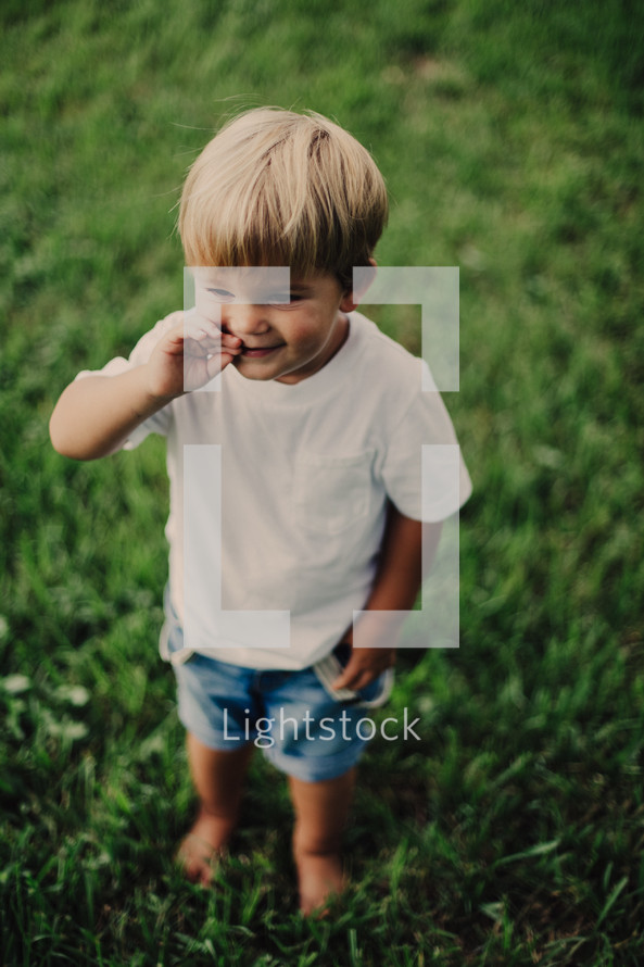 a toddler boy standing barefoot in the grass 