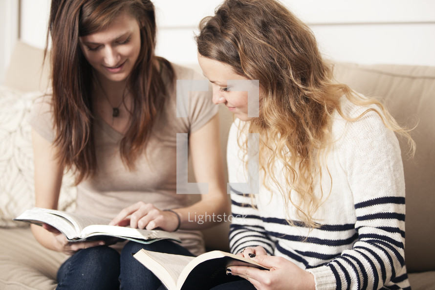 Friends reading a Bible together on a couch. 