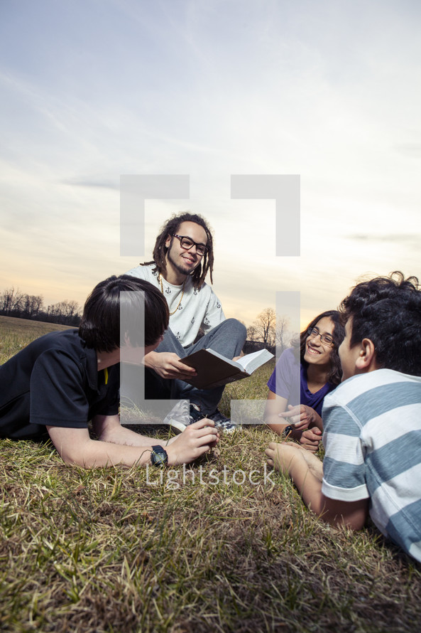 young man reading a Bible to a group of children 