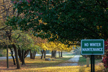 fall scene with fall trees and a sign that reads no winter maintenance 