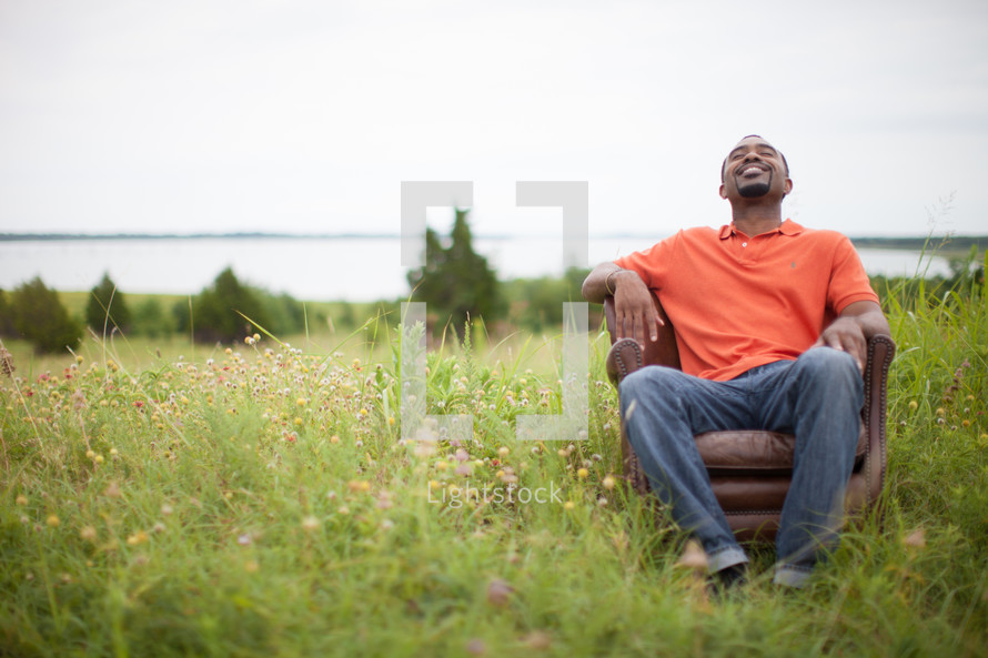 man sitting in a chair in a field relaxing outdoors 