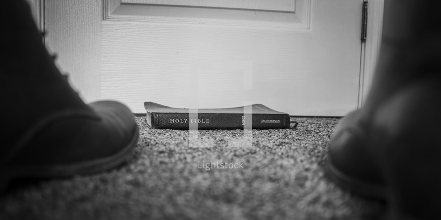 a Bible on a floor in front of a door 