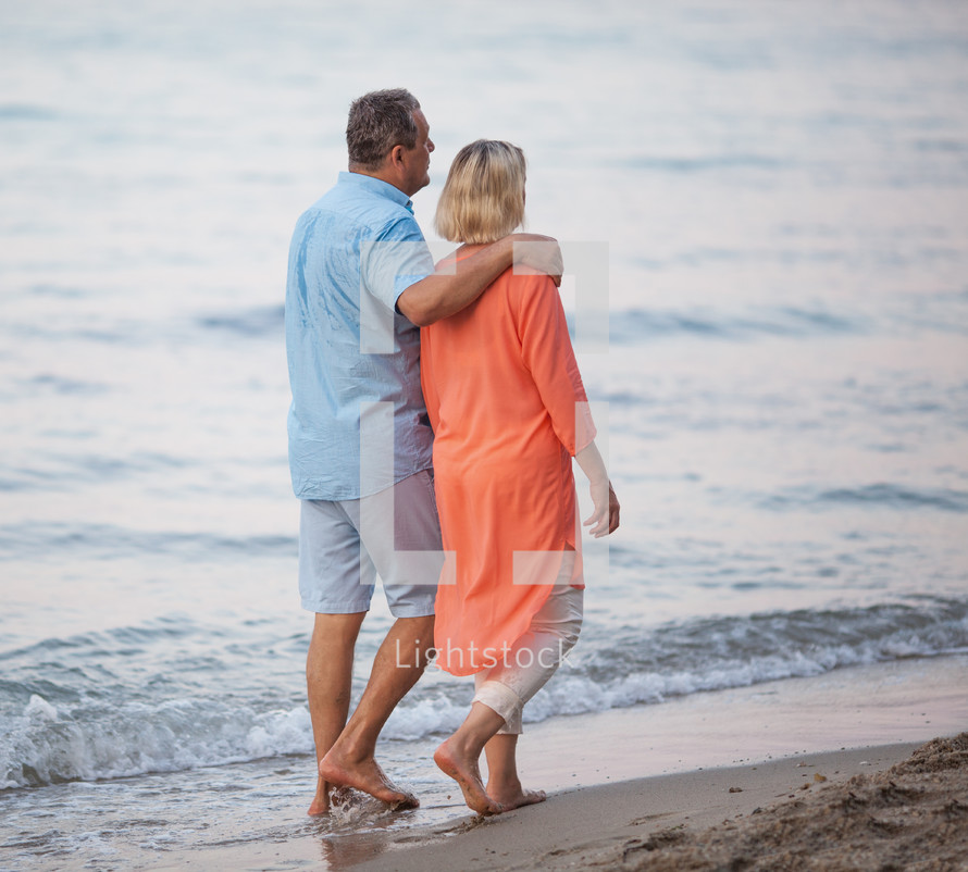 Senior couple enjoying barefoot walk at the seaside