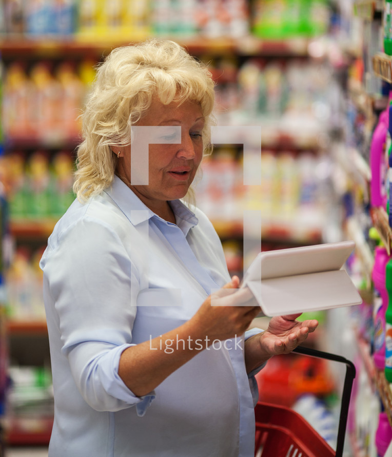 Woman using tablet PC in household chemicals section