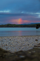 rainbow over islands and a sandy shore 