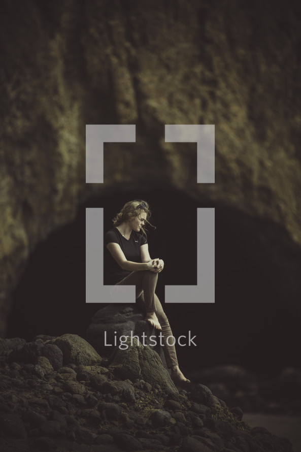 woman sitting alone on a rock in a cave 