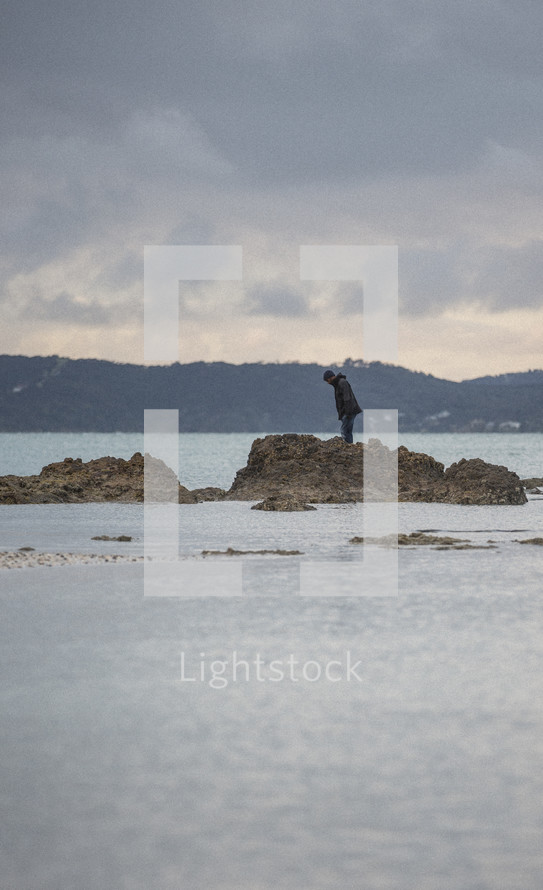 man standing on rocks in shallow water 