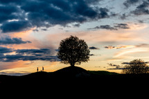 silhouettes of people standing on a hill 