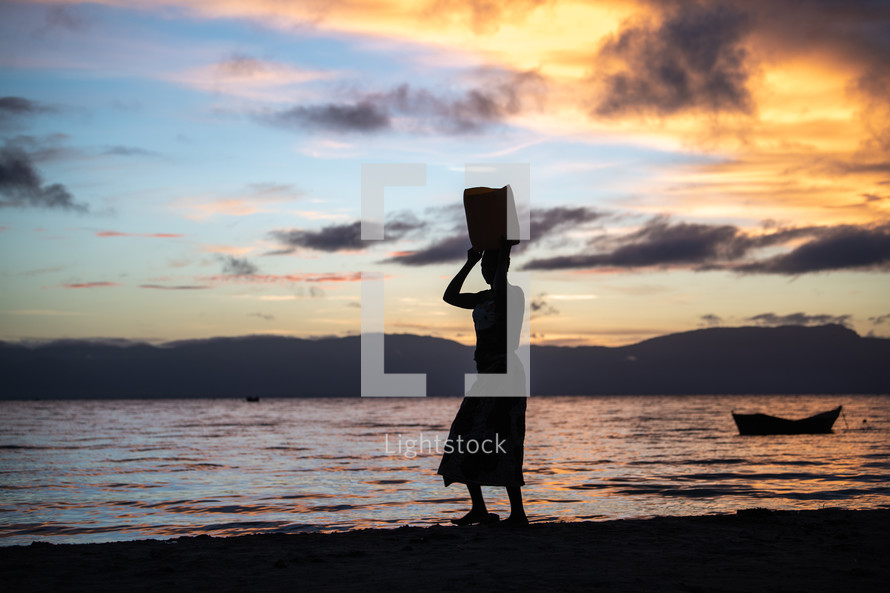 a woman standing on a beach at sunset 