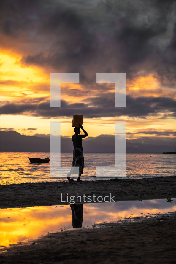 woman standing on a beach at sunset