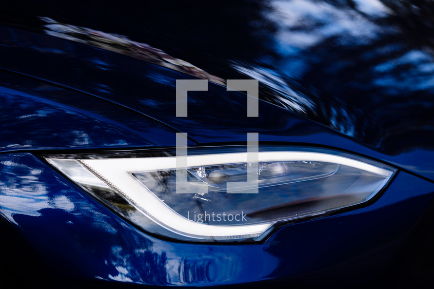 Closeup of new projector headlight on the modern blue car
