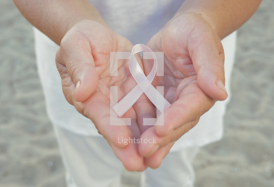 Hands holding pink ribbon
