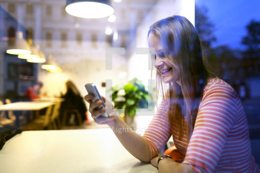 Young woman sitting in a restaurant using mobile
