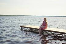woman sitting on a dock reading a Bible 