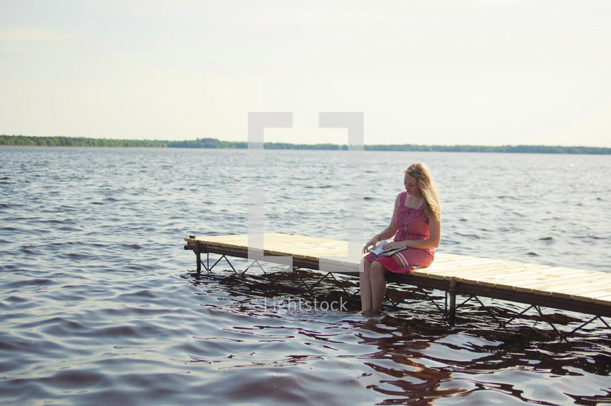 woman sitting on a dock reading a Bible 