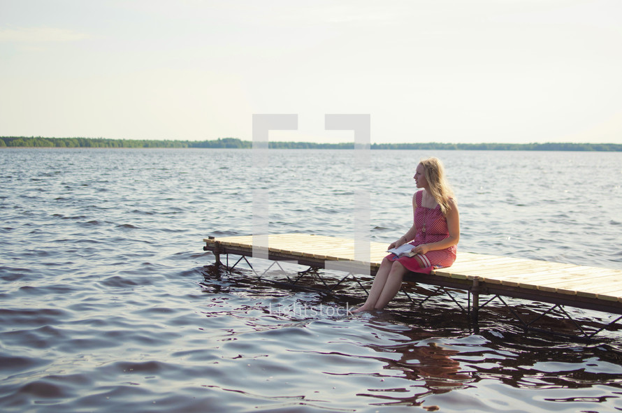 woman sitting on a pier reading a Bible 