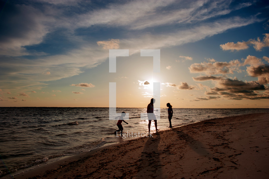 silhouettes of a family on a beach at sunset 