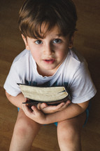 Little boy holding a Bible to his chest.