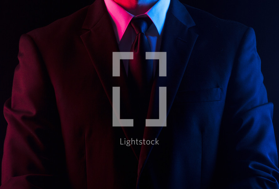 Red and blue light shining on a man in a suit and tie.