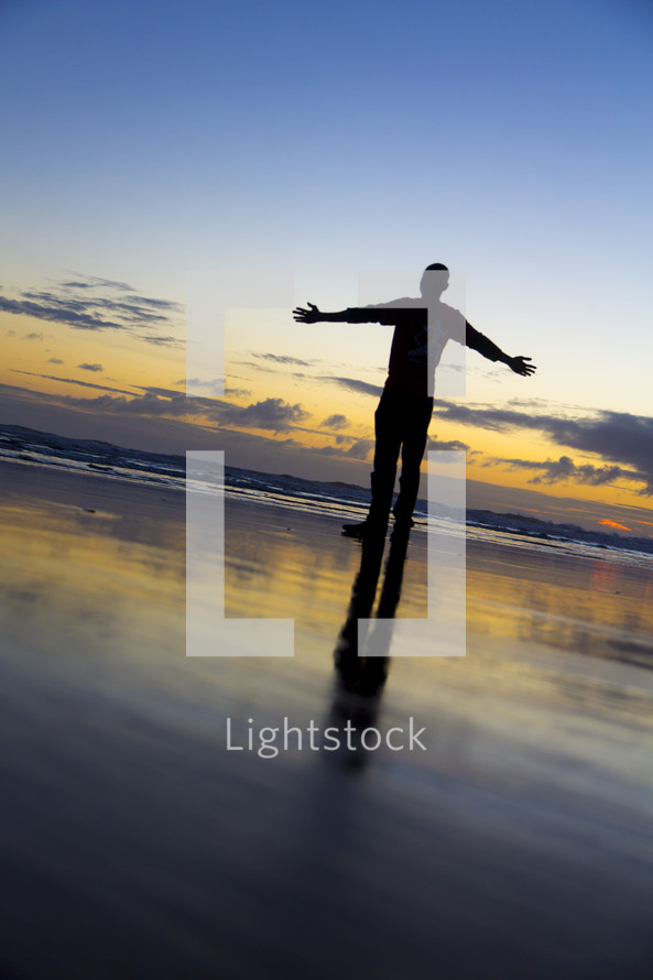 man with open arms standing on a beach 