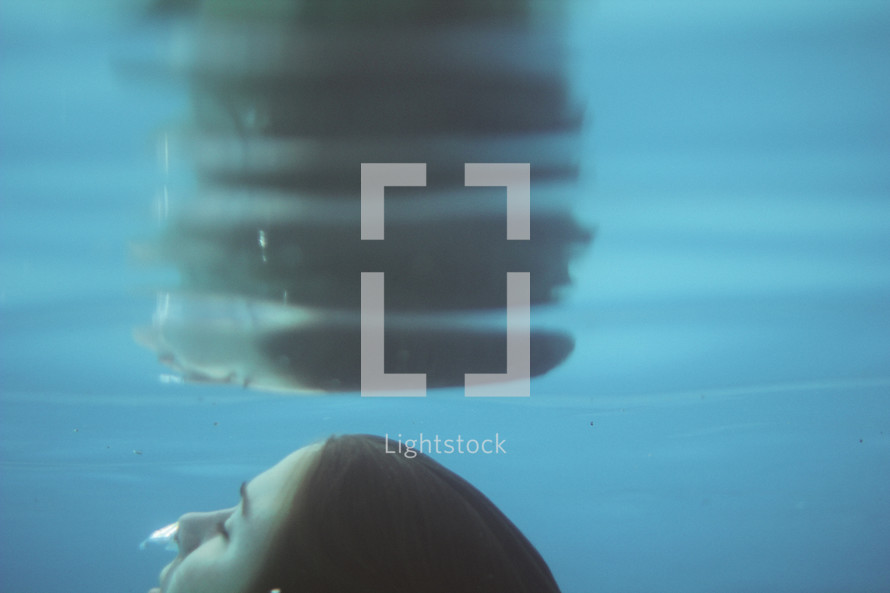 a girl swimming under water rising to the surface 