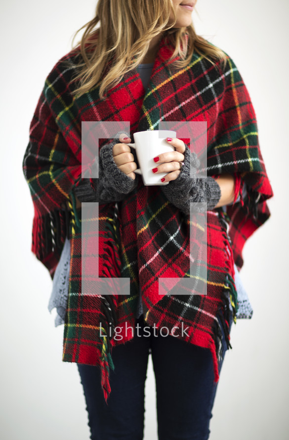a woman in a red plaid shawl holding a mug 