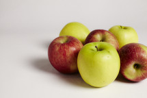 A cluster of green and red apples on seamless white