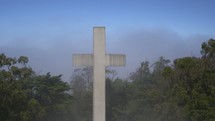 A white cross in the forest with fog