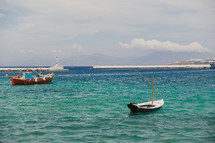 Two small boats floating on a blue and green sea.