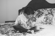 a big brother holding his newborn baby brother 