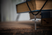cross necklace on a stack of books and Bible 