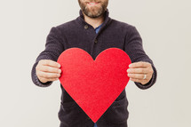 man holding a paper heart cutout